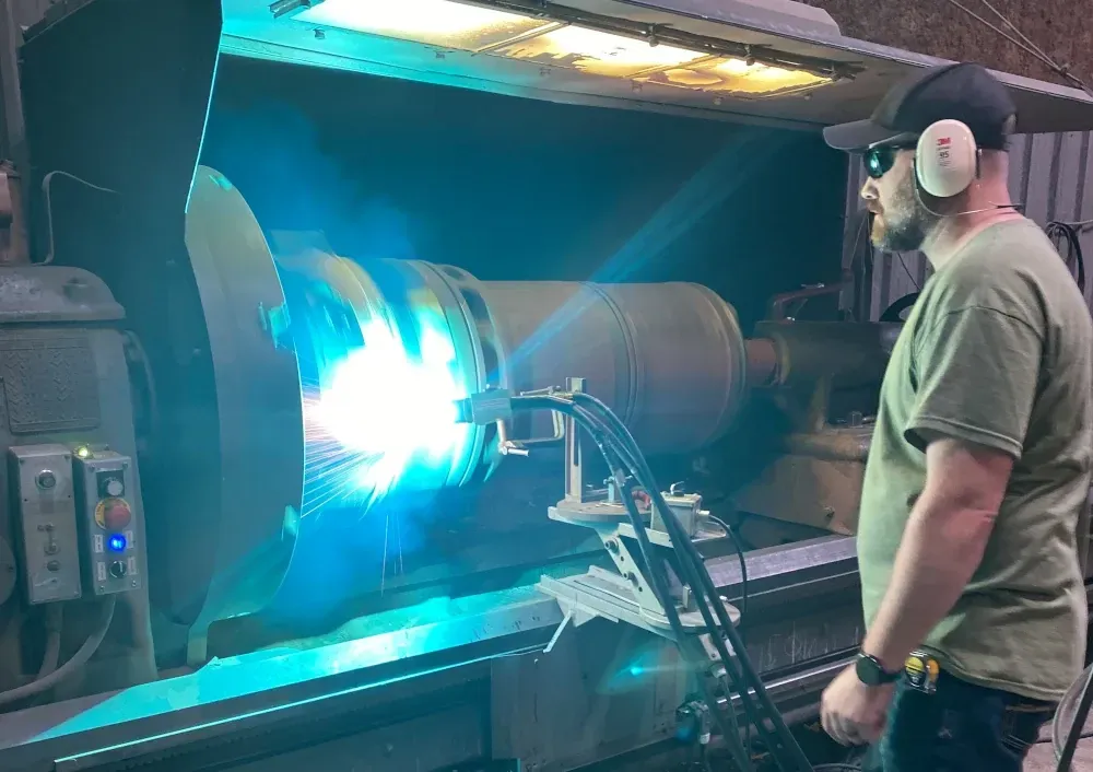 A man watching a part be coated using the Arc Spray process.