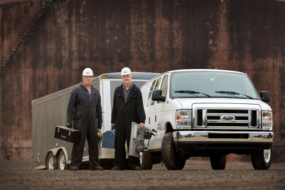 Two Exline employees standing in front of a ford van.