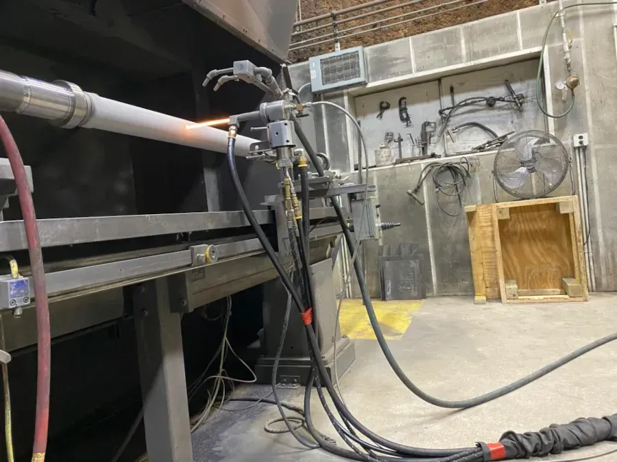 A metal tube being coated with the High Velocity Oxy-Fuel spray process.