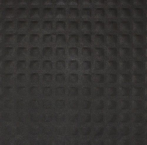 A black mat with holes in it is laying on a white surface.