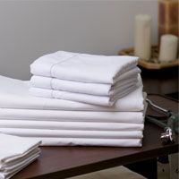 A stack of white towels sitting on top of a wooden table.