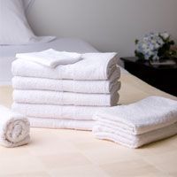 A stack of white towels sitting on top of a bed.