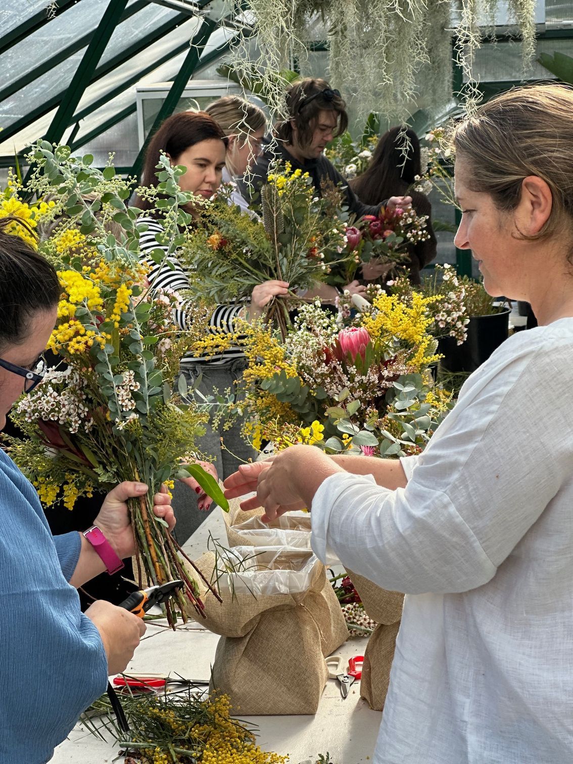 A Group Of Women Are Sitting At A Table Making Flowers — Burnetts On Barney in Kiama, NSW