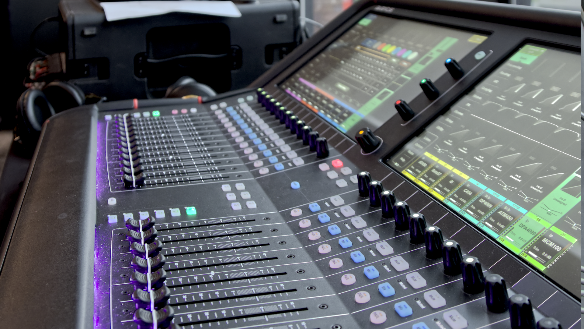 Digital audio mixing console with large touchscreen, illuminated buttons, and faders.