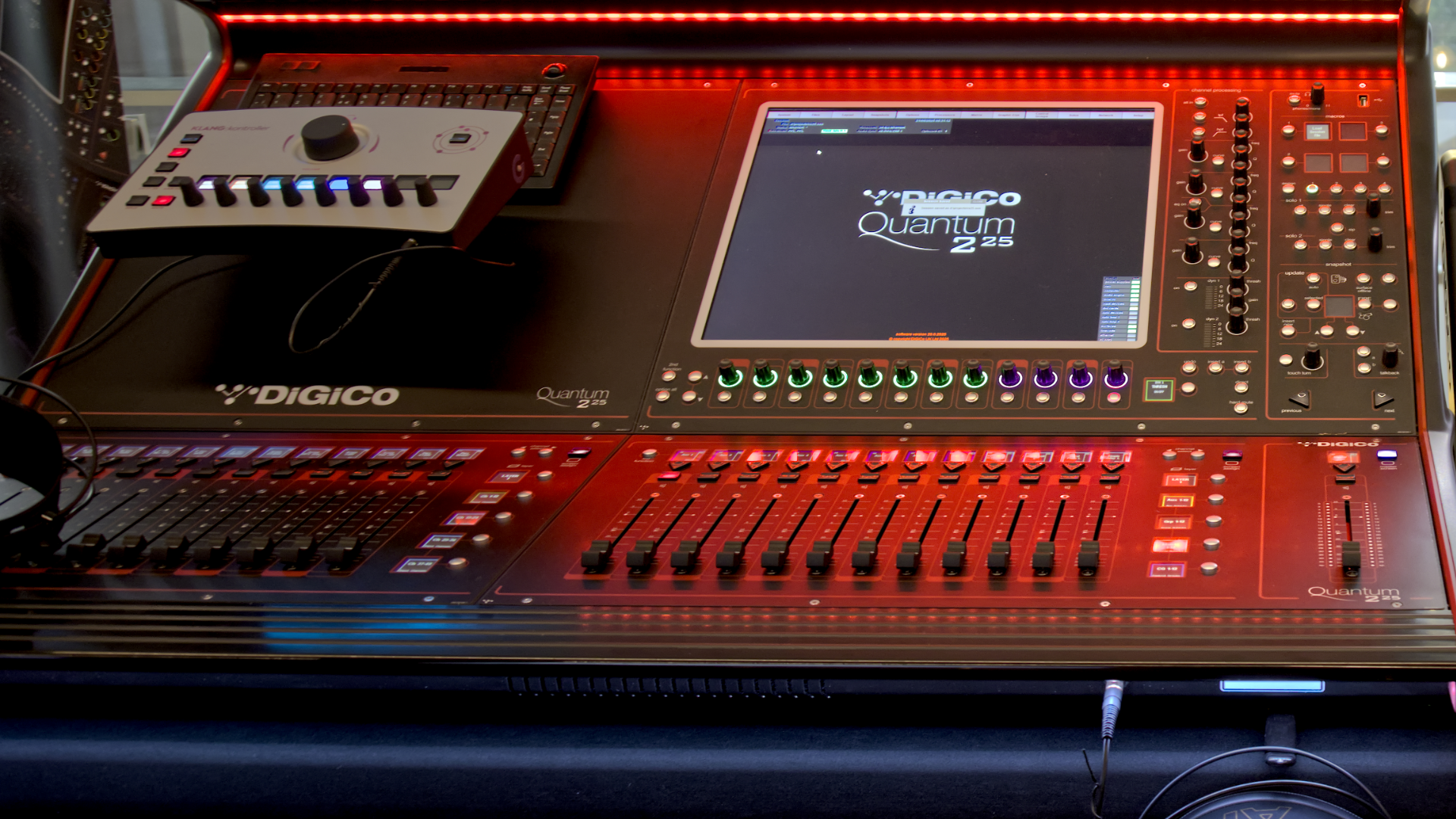 A DiGiCo Quantum audio mixing console with sliders, screen, and control panel, lit by red LEDs.