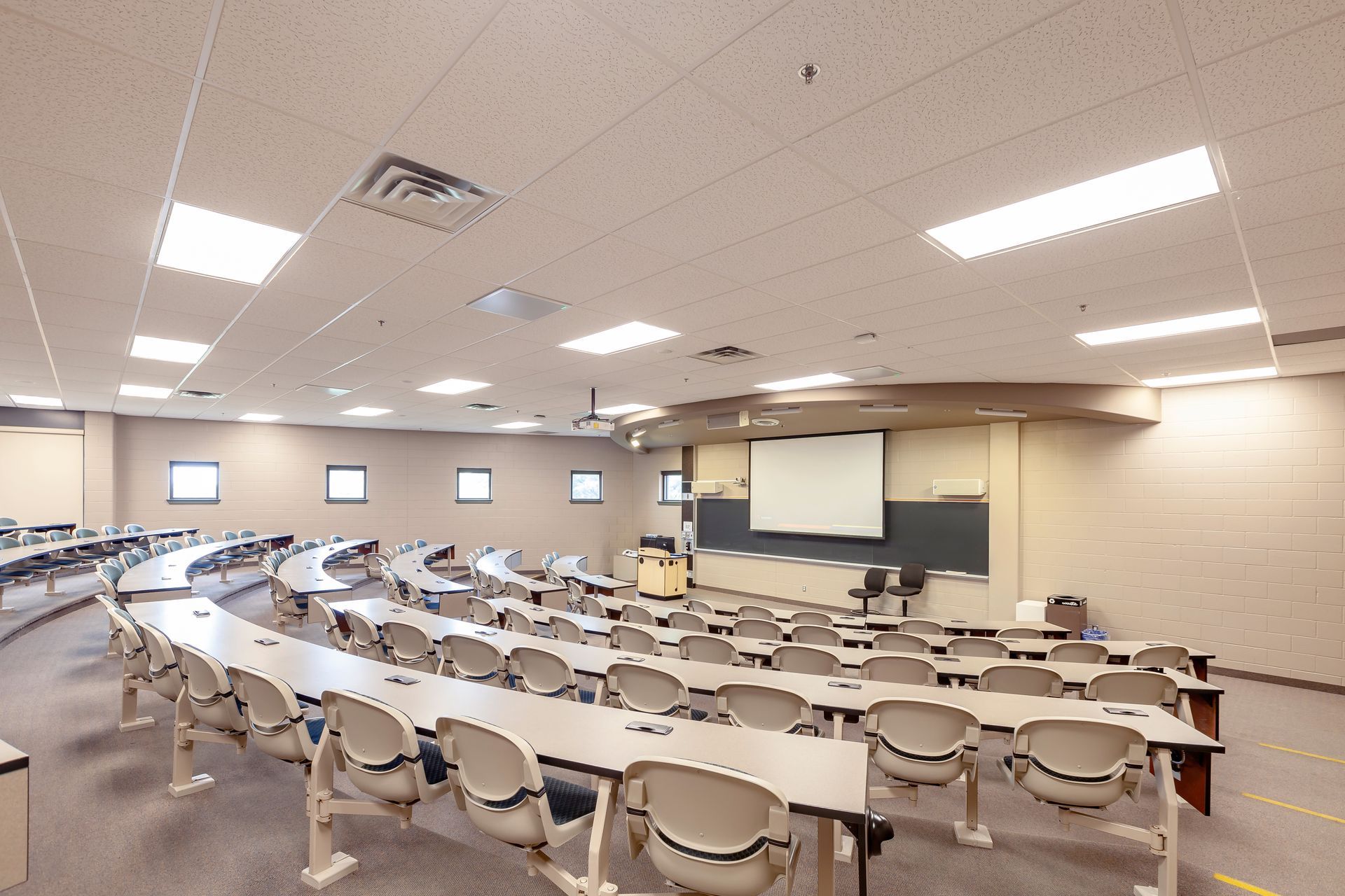 A conference room with a large screen on the wall and a wooden table.