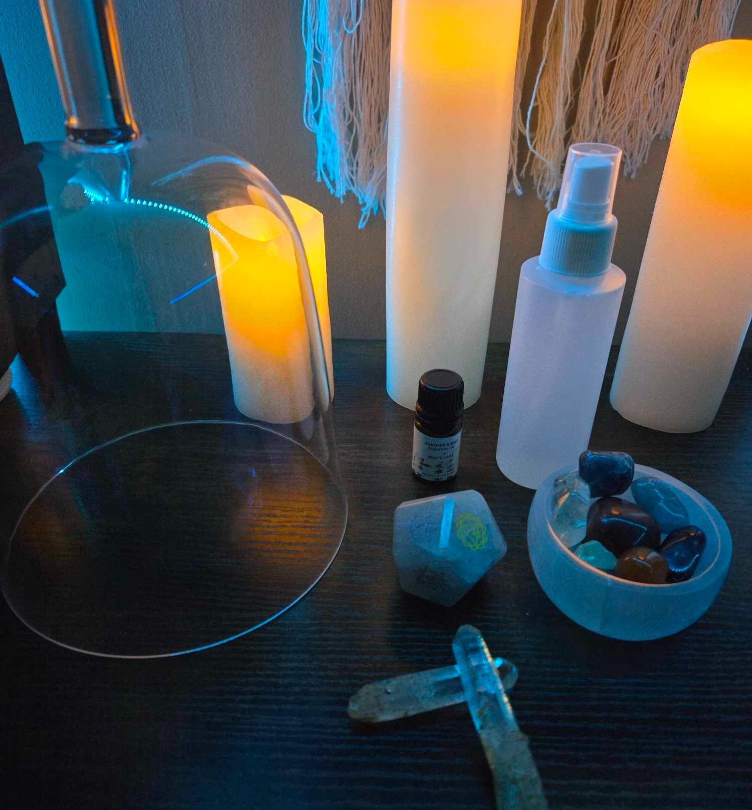A table with candles spray bottles and crystals on it
