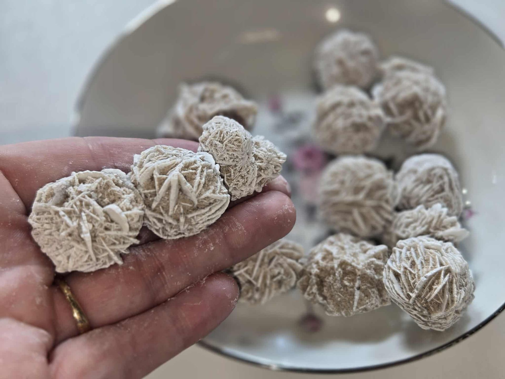 Desert rose crystals in a decorative bowl on a white surface.