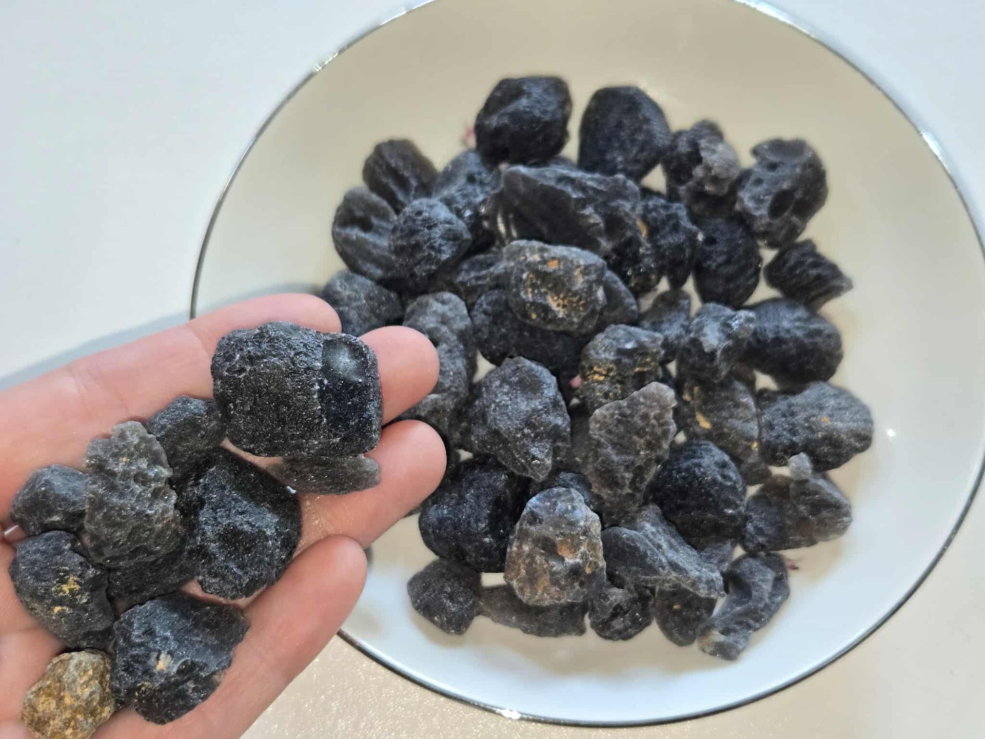 Dried black fruit in a white bowl.