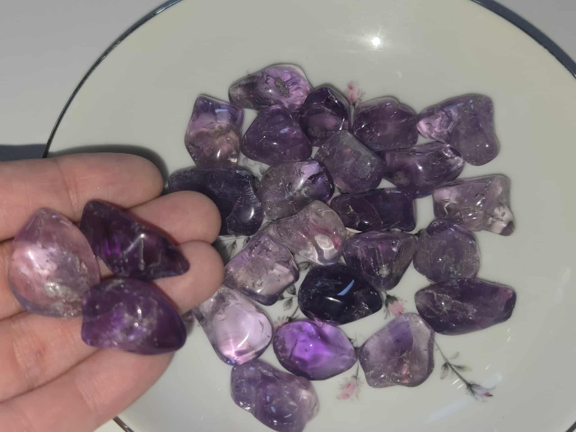 Amethyst crystals in a white bowl with floral design.
