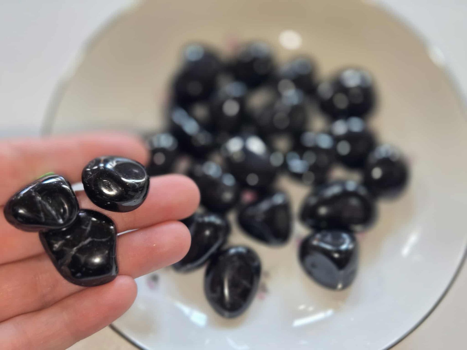 Black polished stones in a white bowl with floral designs.