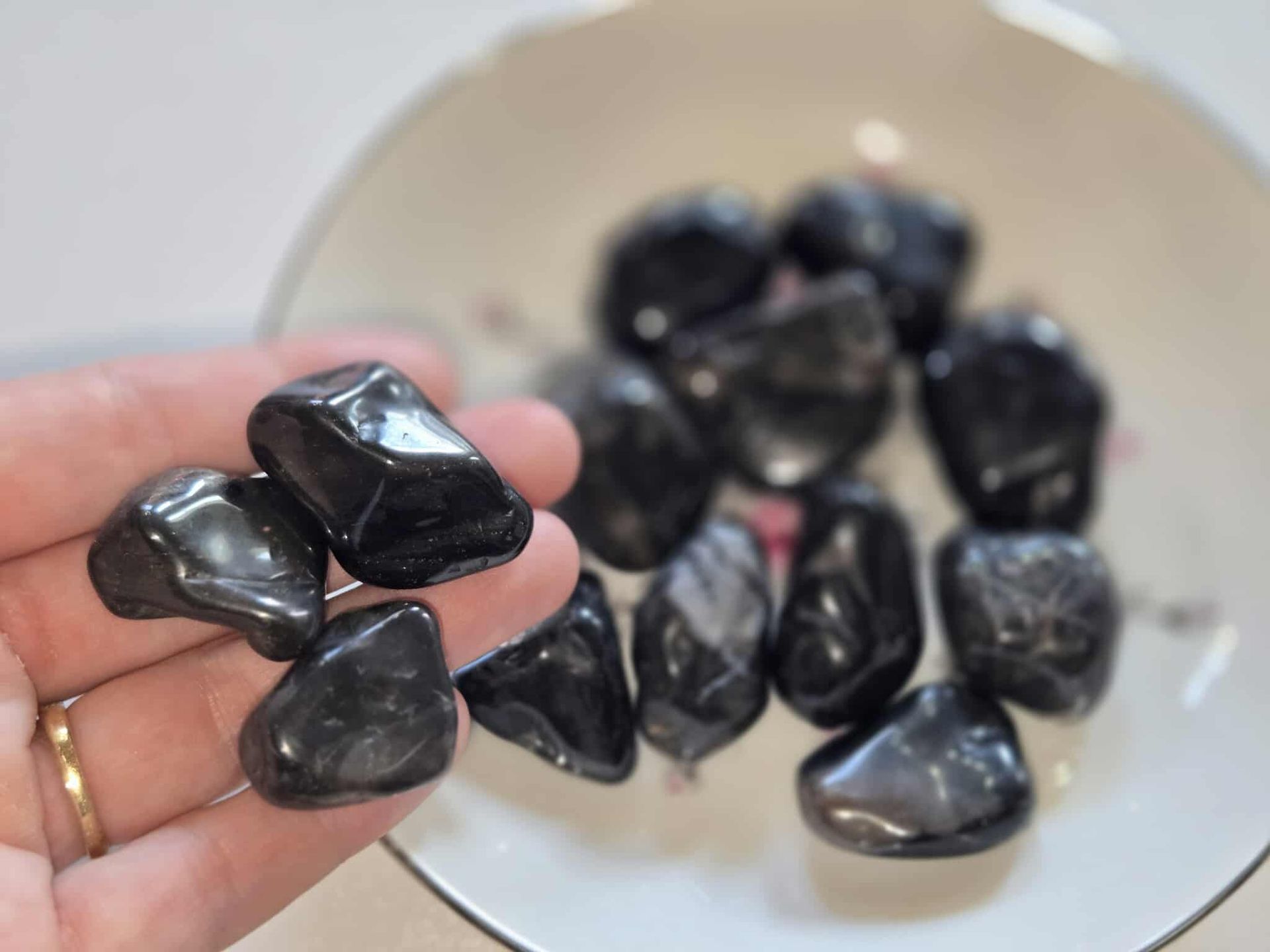 Black, polished stones in a floral patterned, white teacup.