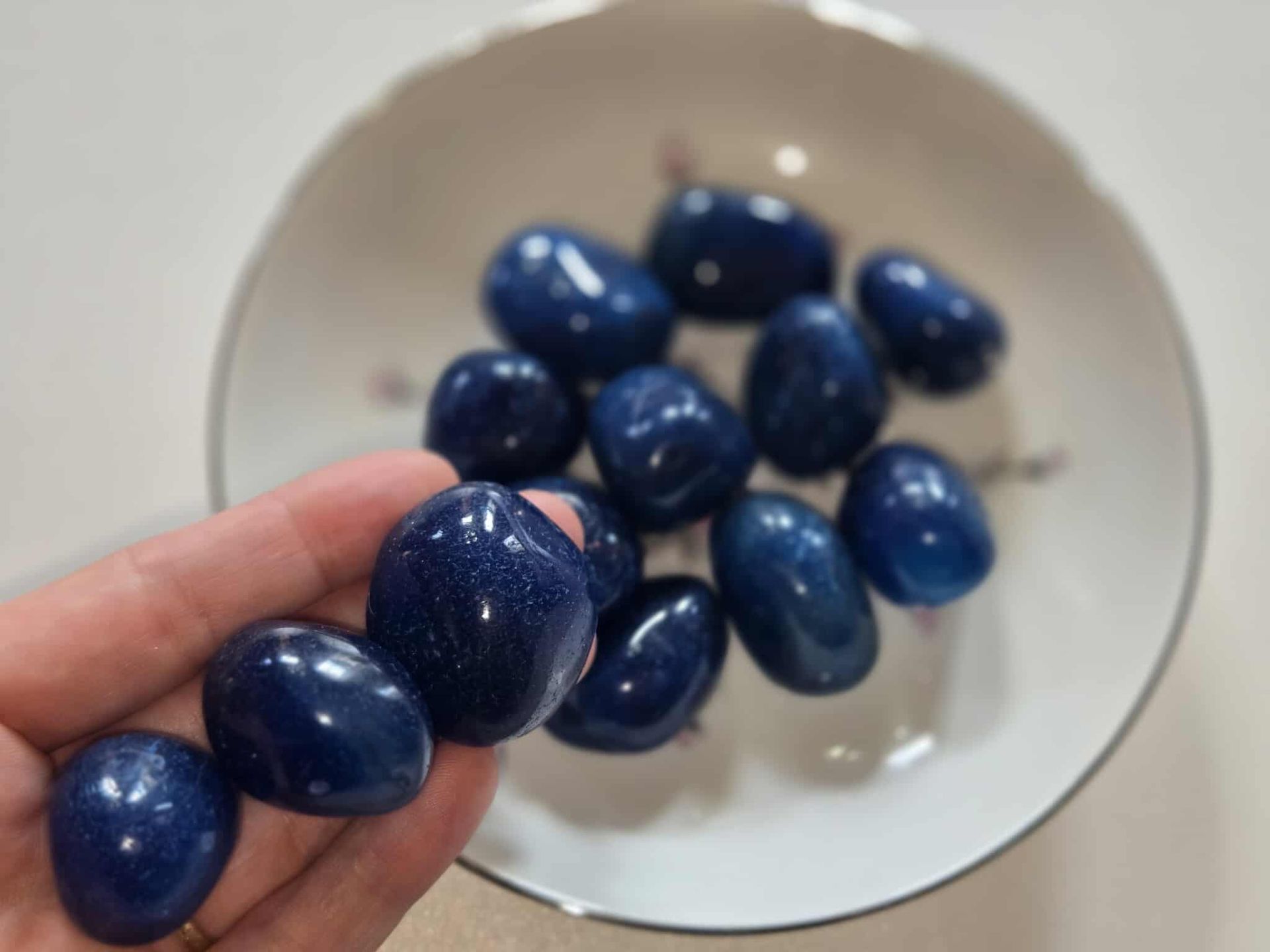 Blue goldstone tumbled stones in a white decorative dish.