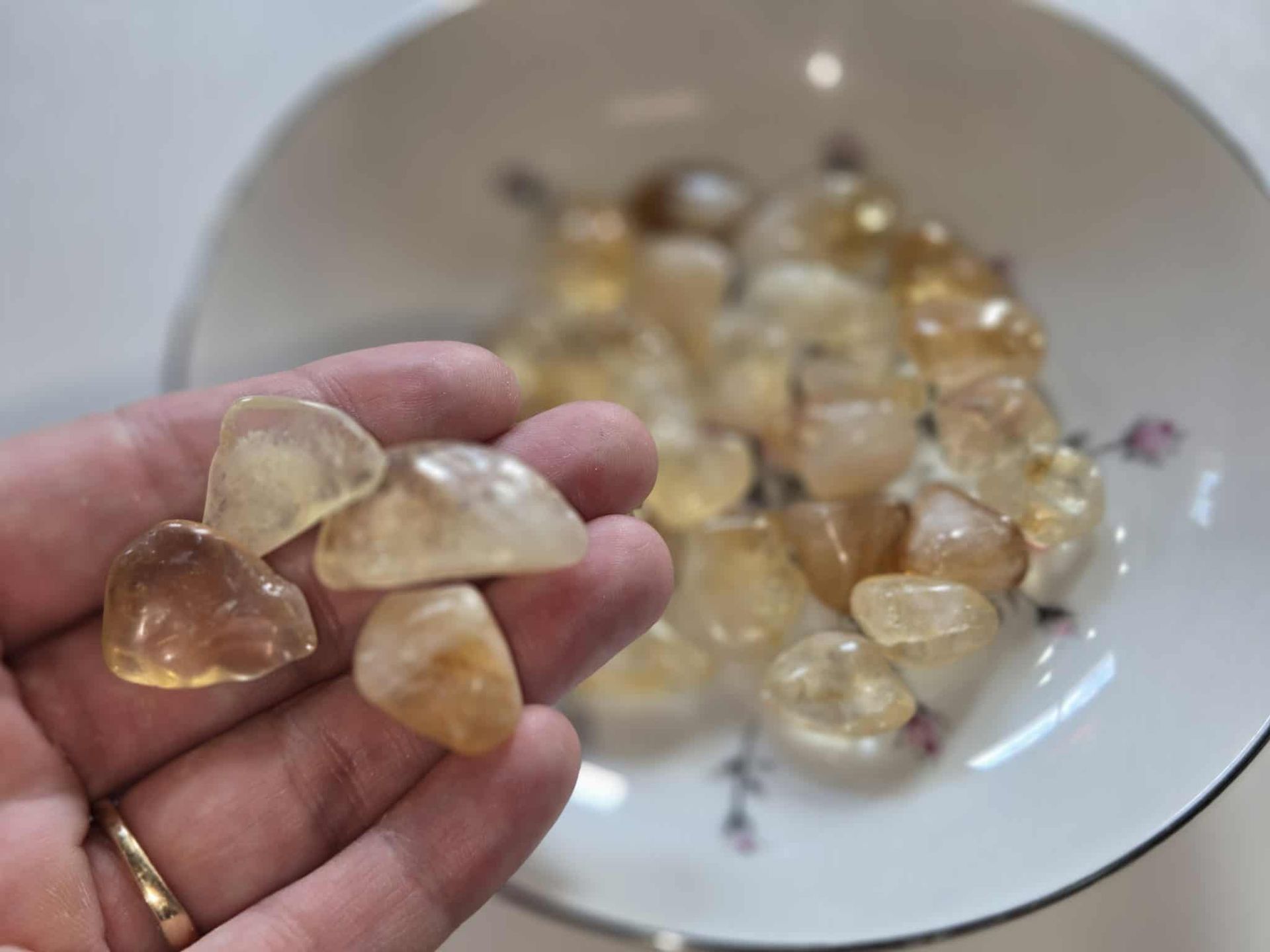 Bowl of yellow-orange citrine crystals on a white plate with a floral design.