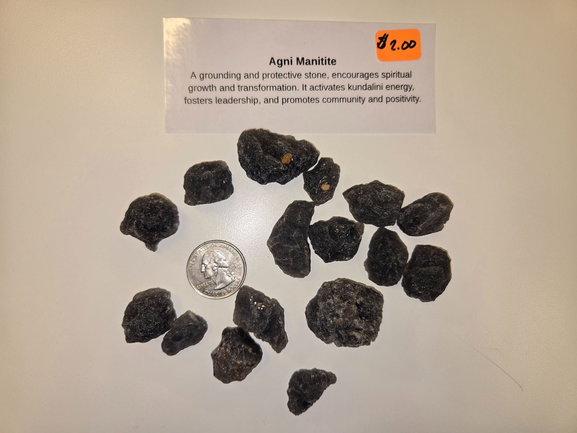 A pile of black rocks next to a dime and a sign that says april mantra
