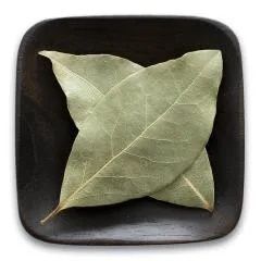 Bay leaves on a black plate on a white background.