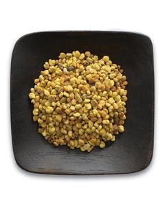 A wooden bowl filled with a pile of corn on a white background.