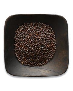 A wooden bowl filled with black pepper on a white background.