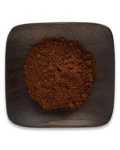 A wooden bowl filled with brown powder on a white background.