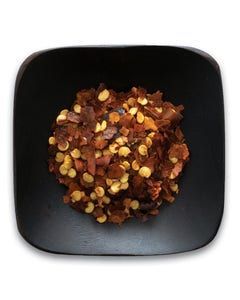 A black bowl filled with chopped red peppers on a white background.