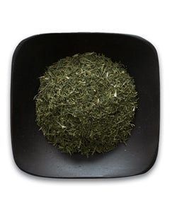 A black square plate topped with a pile of green tea leaves.