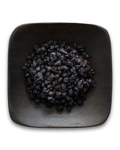 A black bowl filled with black beans on a white background.
