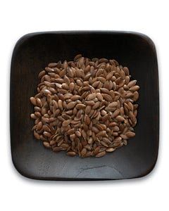 A wooden bowl filled with flax seeds on a white background.