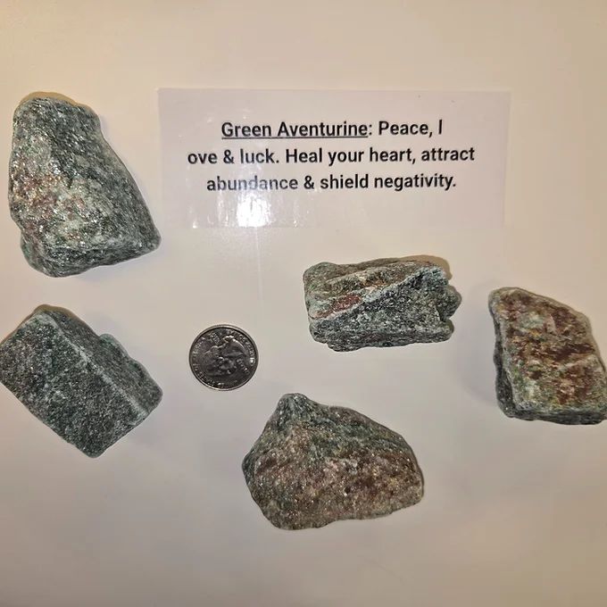A collection of rocks with a sign that says green aventurine peace love luck heal your heart attract abundance and shield negativity