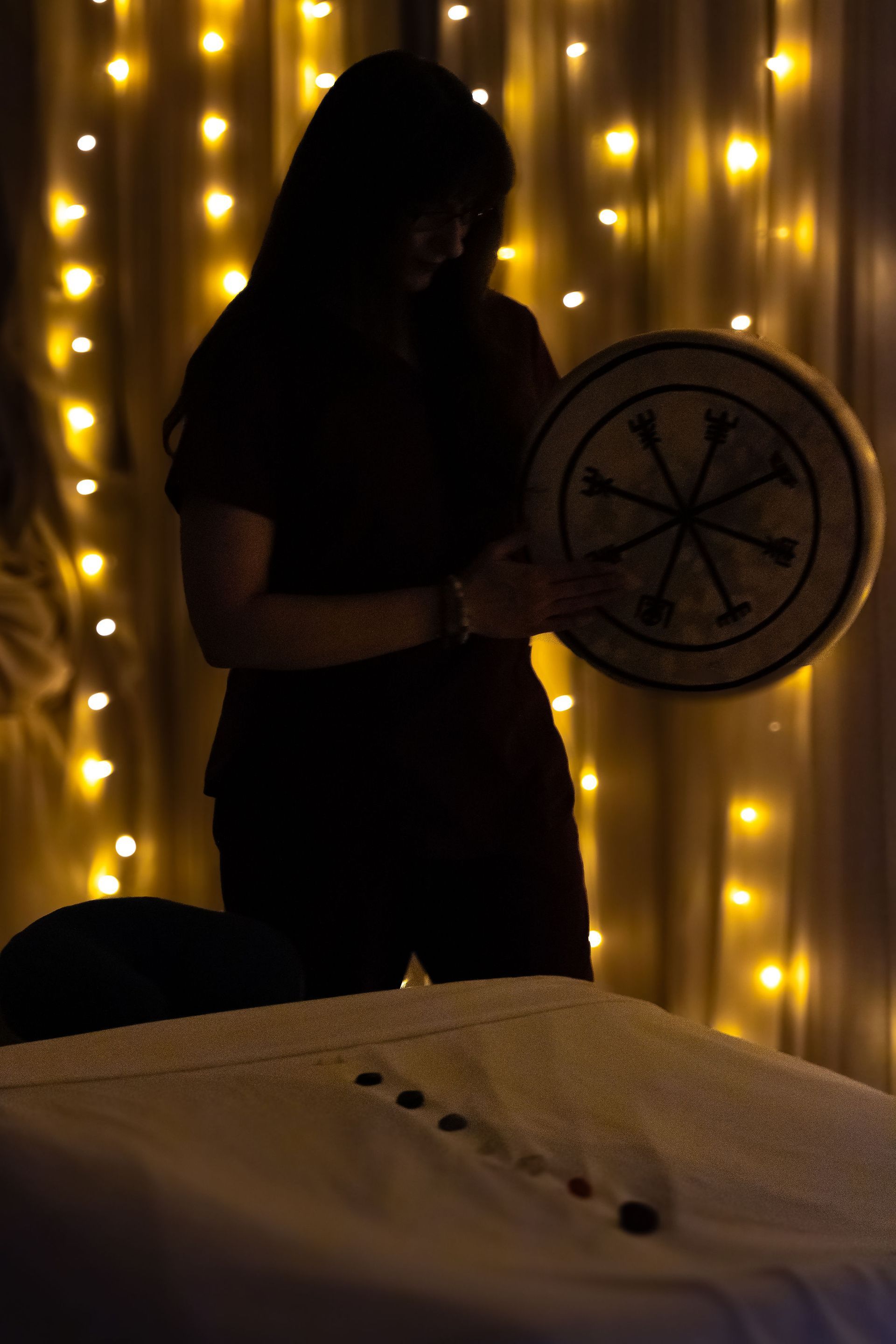 A woman is playing a drum in a dark room.