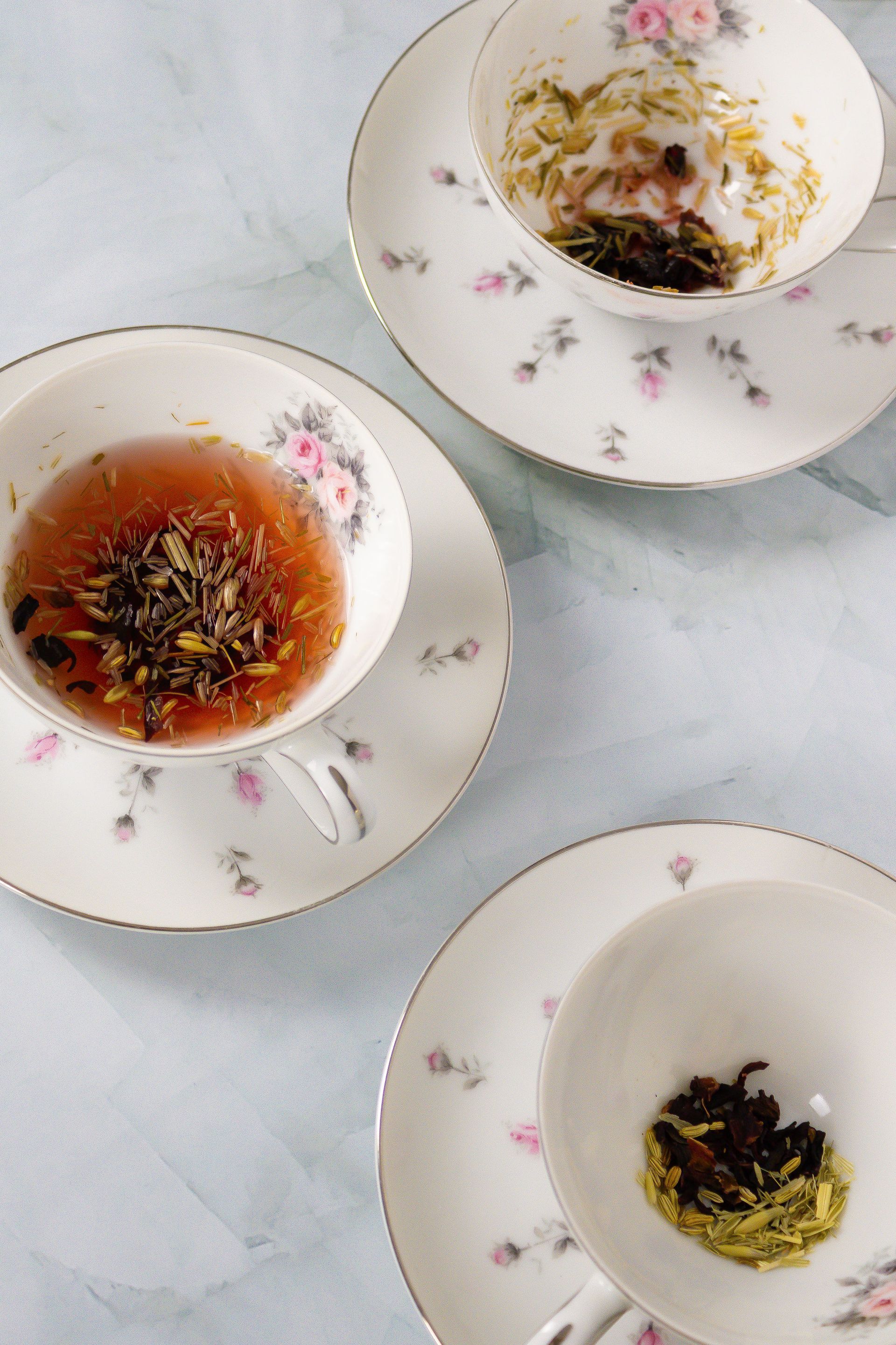 Three cups and saucers filled with different types of tea
