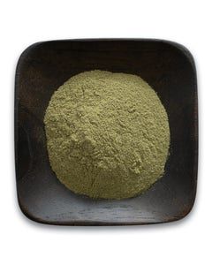 A wooden bowl filled with green powder on a white background.