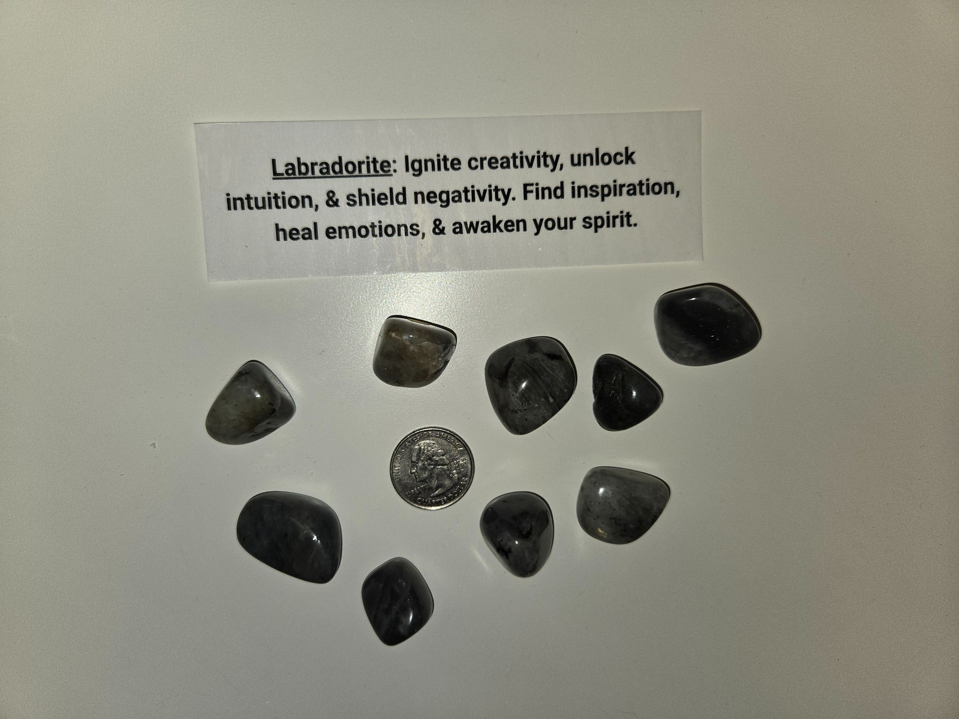 A pile of black rocks with a card that says labradorite lynite creativity unlock