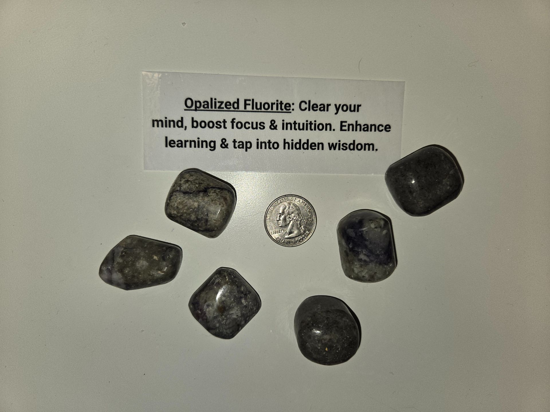 A pile of crystals with a card that says " clear your mind boost focus & intuition enhance learning & tap into hidden wisdom "