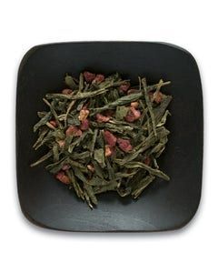 A black square plate topped with green tea leaves and red berries.