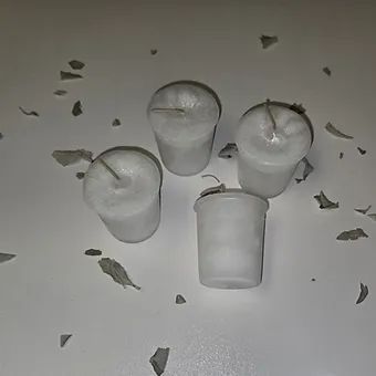 Four white candles are sitting on top of a white table.