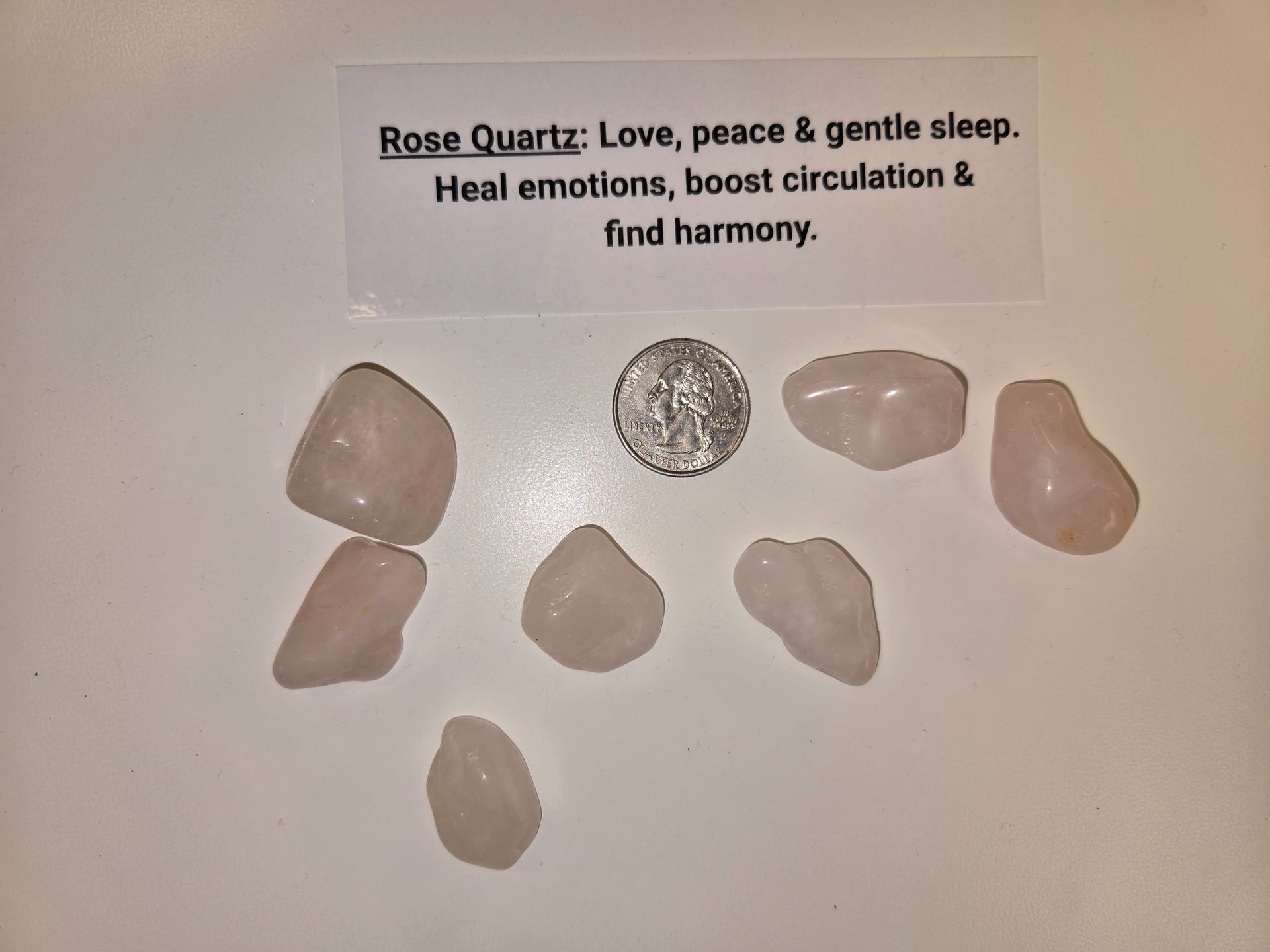 A pile of rose quartz next to a dime