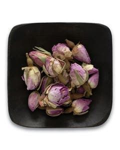 A black bowl filled with purple flowers on a white background.