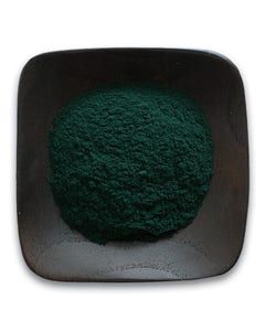 A square bowl filled with green powder on a white background.