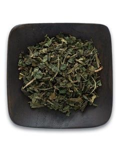 A square bowl filled with dried mint leaves on a white background.