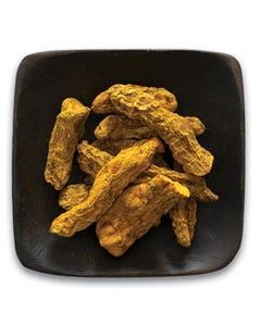 A black plate topped with a pile of turmeric sticks.