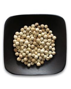 A black plate topped with white peppercorns on a white background.