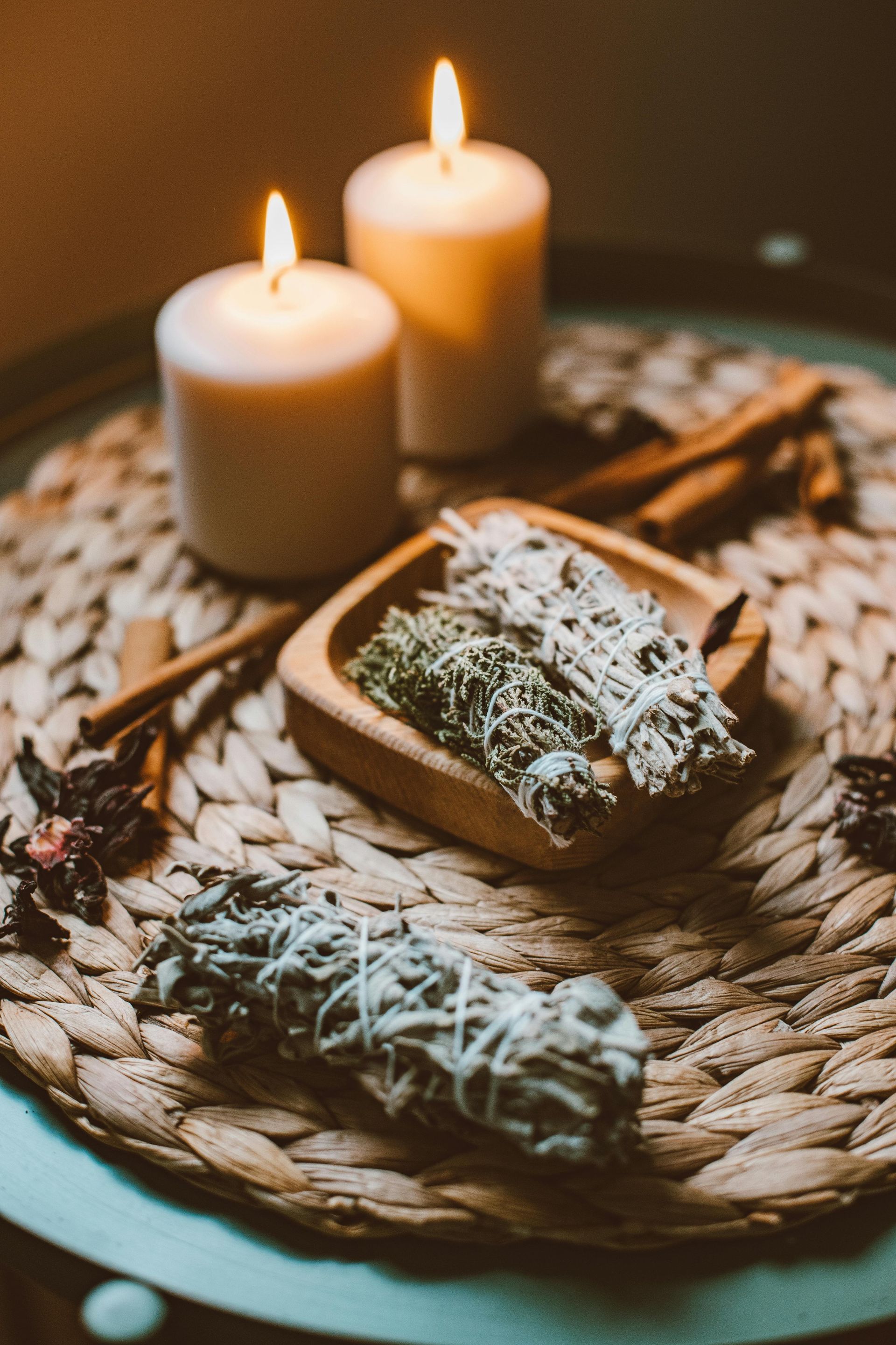 A table with candles , sage sticks , and cinnamon sticks on it.