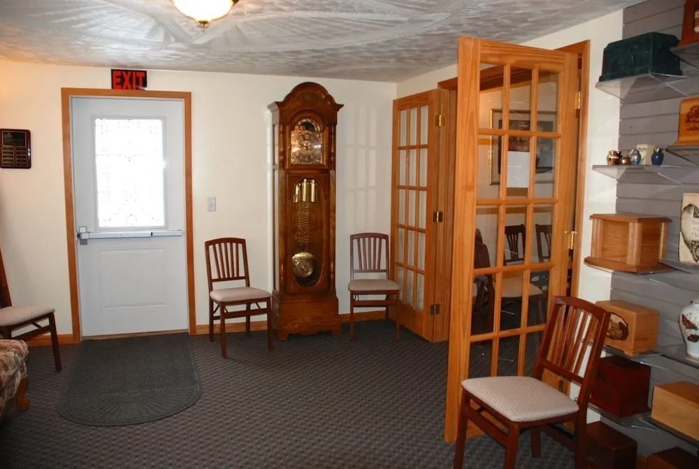 Waiting room with clock, chairs, glass-paned doors, exit sign, and a shelf displaying various items.
