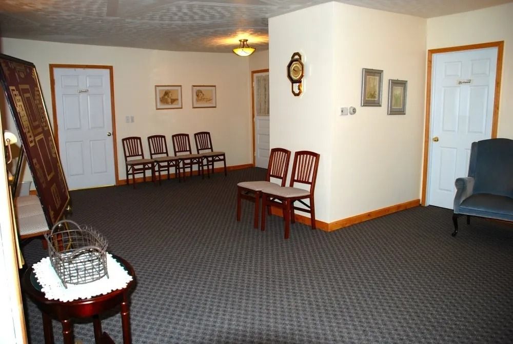 Hallway with doors, chairs, and artwork; dark carpet.