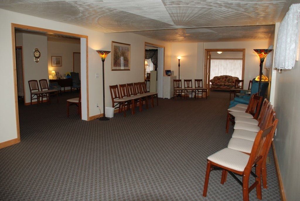 Interior of a funeral home with rows of chairs, carpet, and lamps.