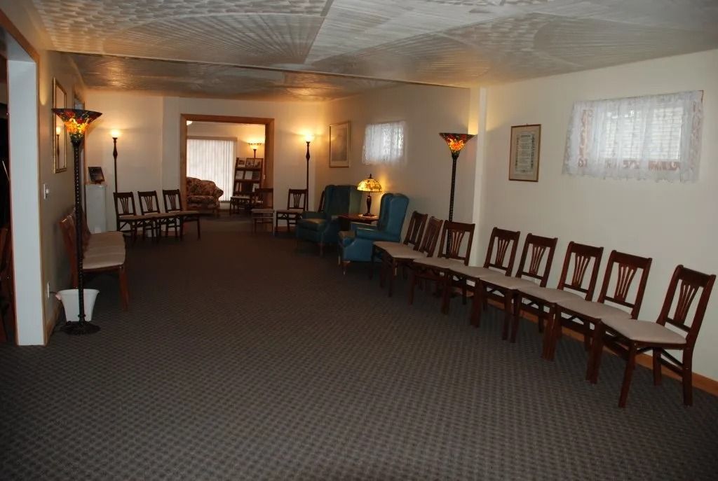 Interior of a waiting room with chairs, lamps, and a patterned carpet and ceiling.