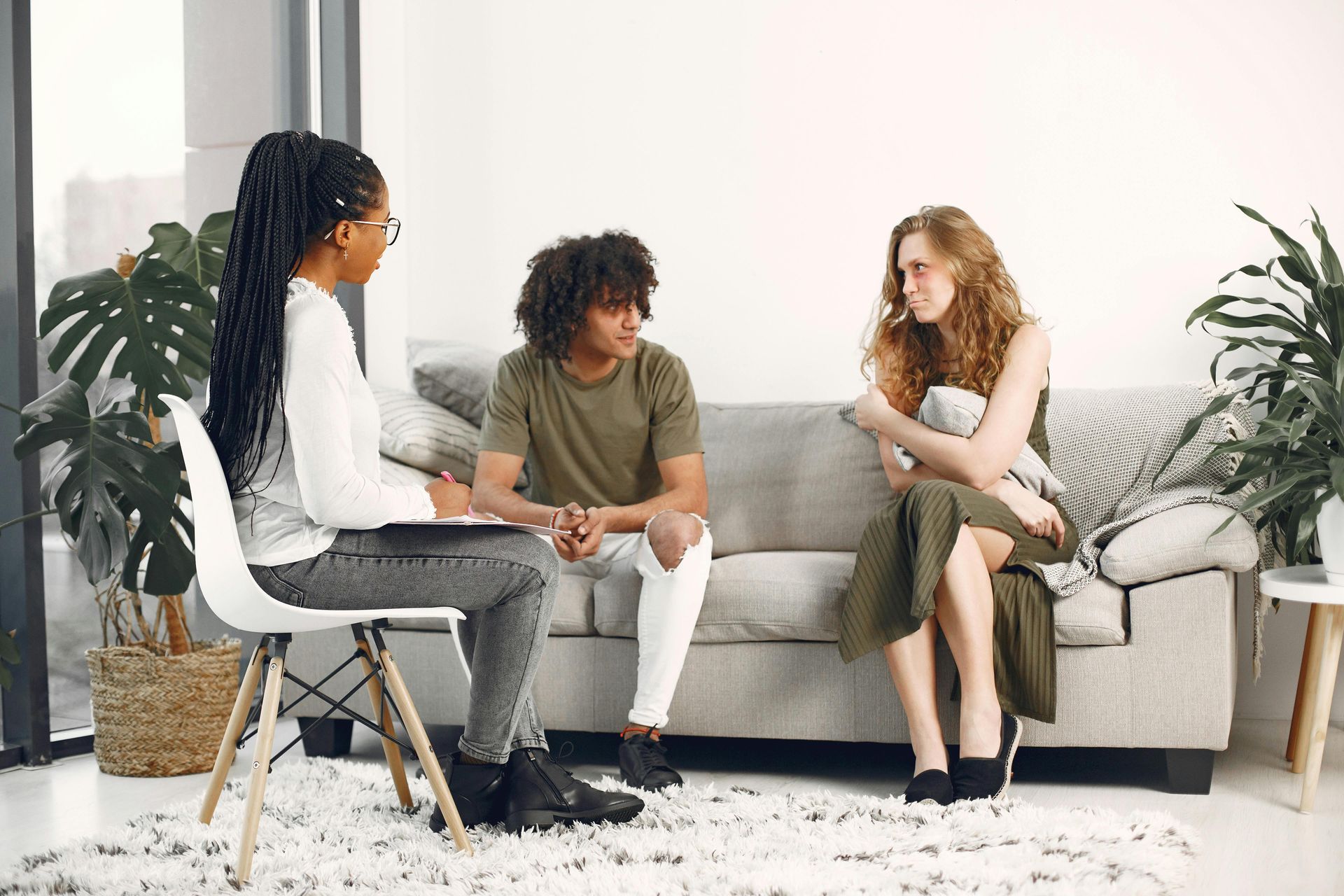 A man and a woman are sitting on a couch talking to a woman.