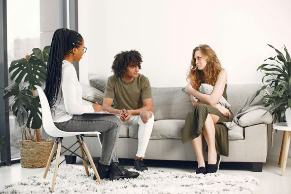 A man and a woman are sitting on a couch talking to a woman.