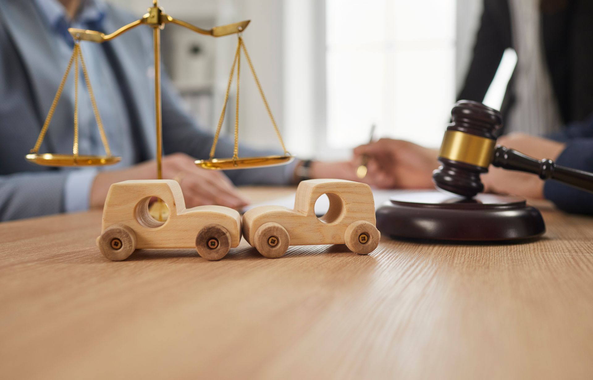Close-up of two small wooden toy cars that have hit each other, standing on an office desk.