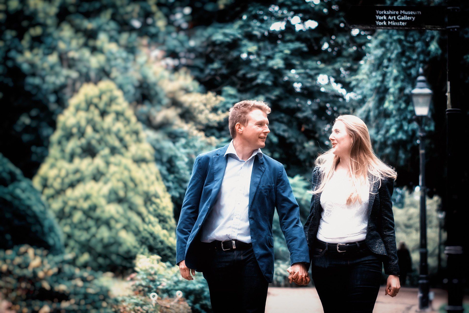 A man and a woman are holding hands and walking in a park.